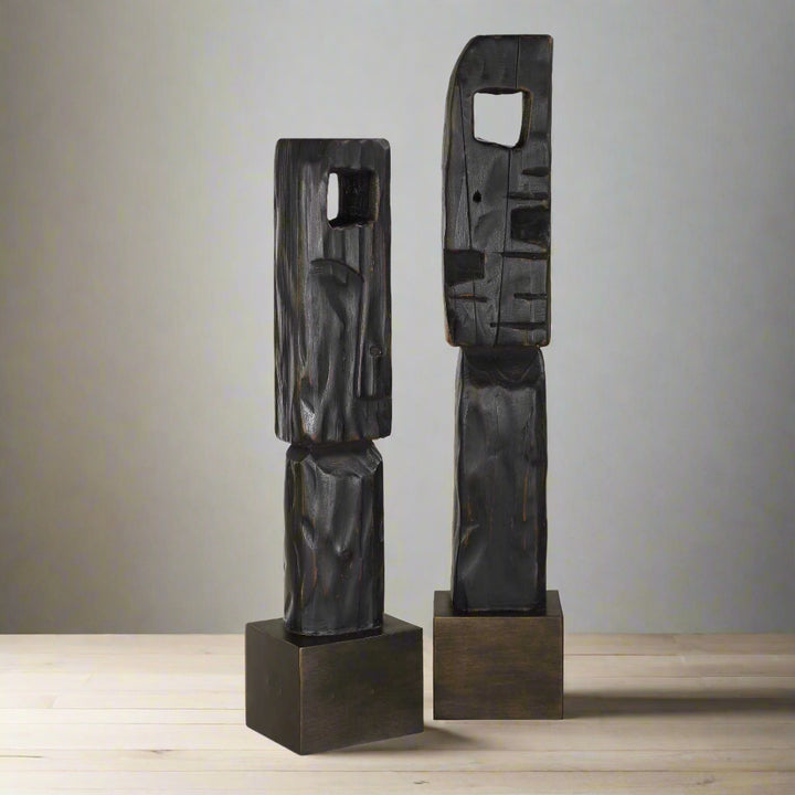 Two abstract black sculptures on square bases against a white background