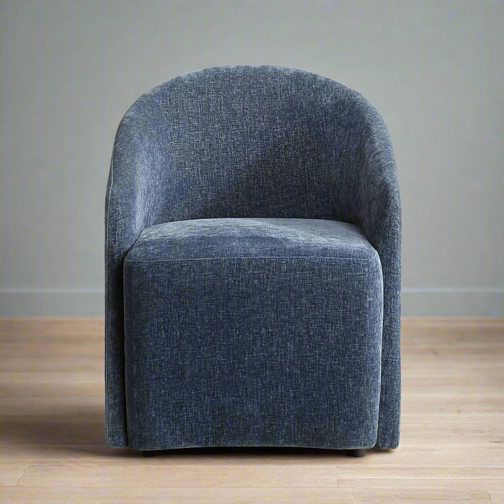 A blue upholstered dining chair with a unique barrel back design and rolling casters.