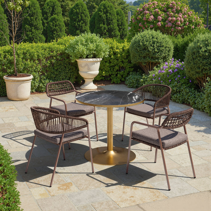 Outdoor patio set with a round table and four chairs on a stone patio.