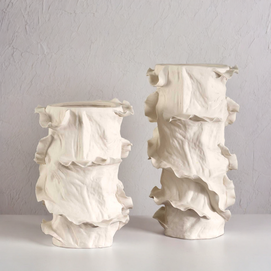Two white ceramic vases with textured surface on a plain background