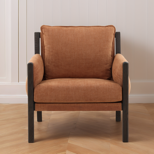 Brown armchair with black frames on a wooden floor and light-colored wall background