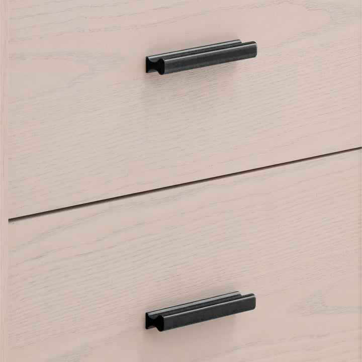 Close-up of a light wood dresser with two drawers, featuring sleek black metal handles.