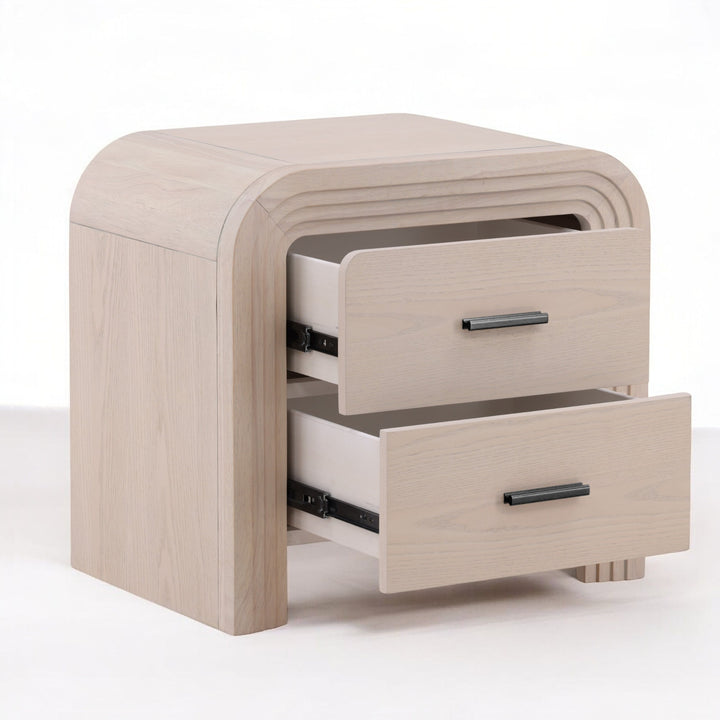 A modern light wood nightstand with a curved design featuring two open drawers and sleek black handles.
