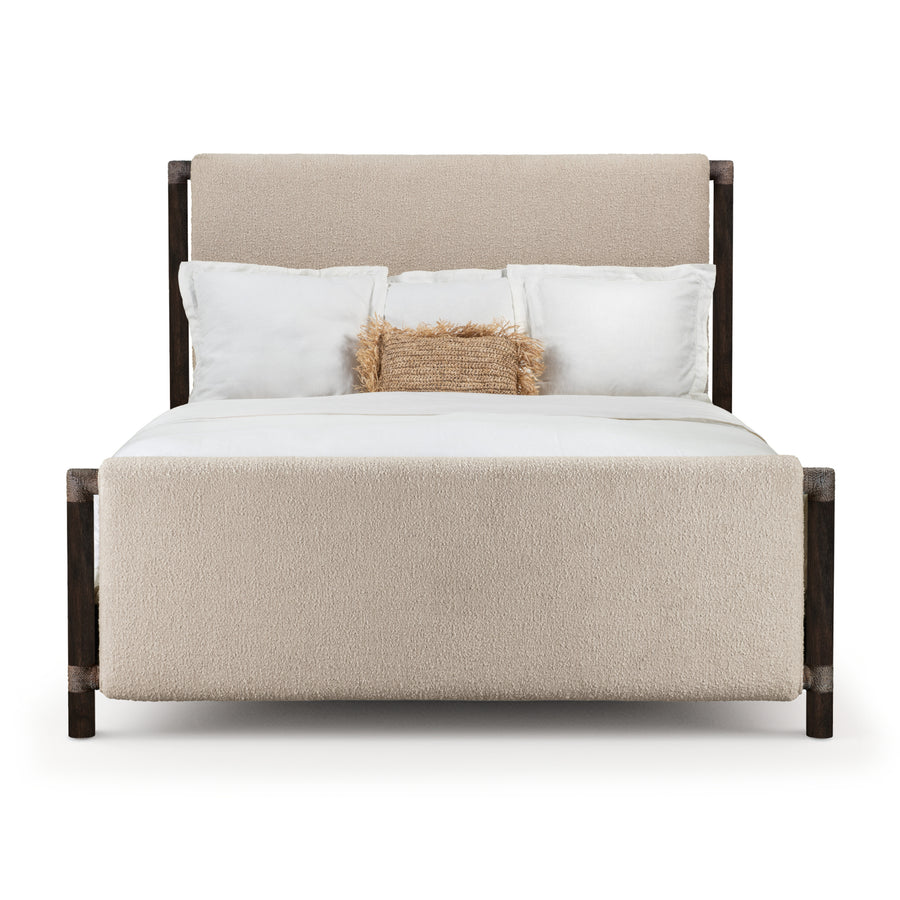 Modern upholstered bed with a soft beige headboard and footboard, featuring dark wooden frame and layered white bedding with decorative pillow.