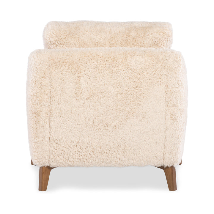 Back view of a cream-colored faux-shearling accent chair with mid-century modern wooden legs.
