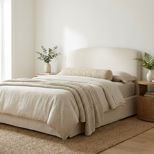 Modern coastal bedroom with a woven rattan bed, neutral linen bedding, and warm, minimalist decor.
