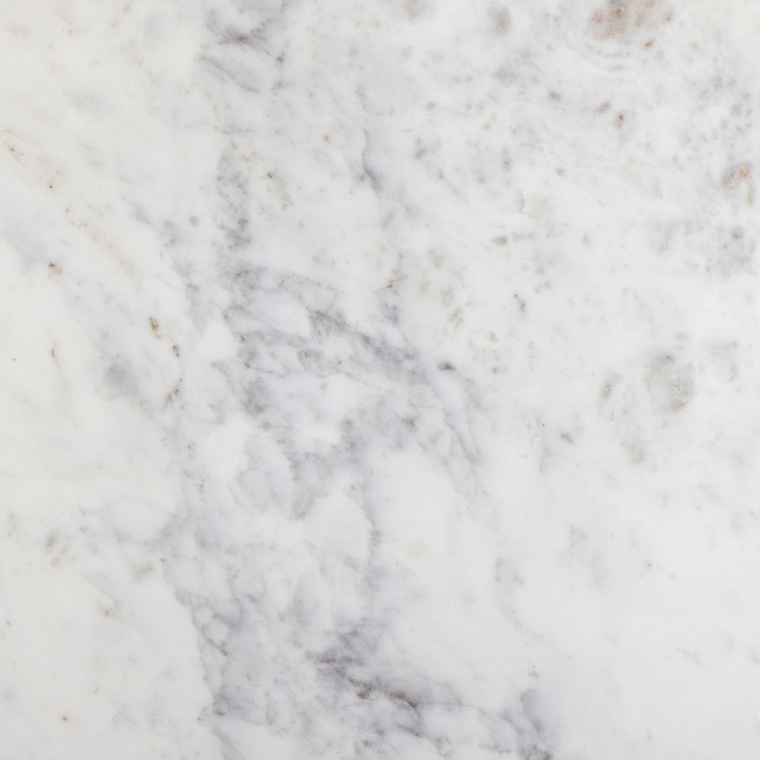 Close-up of a smooth, white marble surface featuring subtle gray veining and natural imperfections, creating an elegant texture.