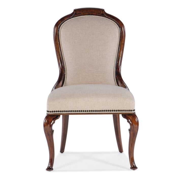 An upholstered chair with beige textured fabric, bronze nailhead trim, and carved cabriole legs finished in cherry wood.