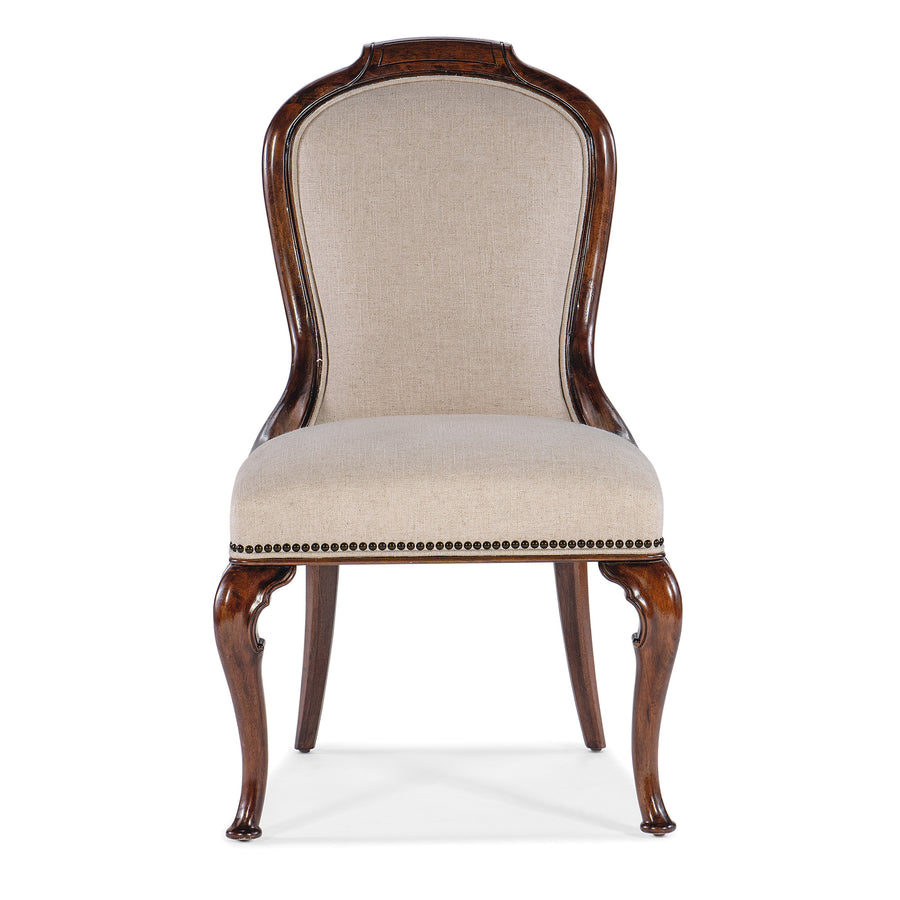 An upholstered chair with beige textured fabric, bronze nailhead trim, and carved cabriole legs finished in cherry wood.