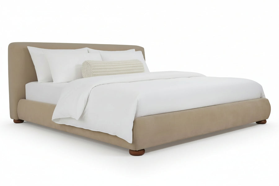 beige upholstered bed frame, white linens, cylindrical textured pillow, white background