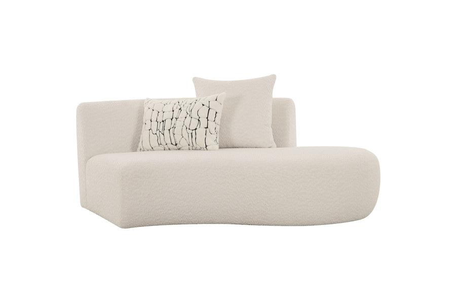 A modern, plush white chaise lounge featuring soft curves, with two textured pillows.