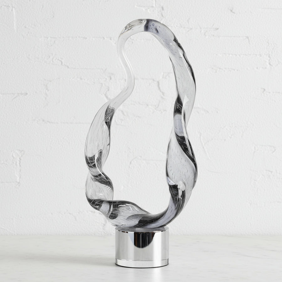 Clear glass decorative item with twisted design on a white background