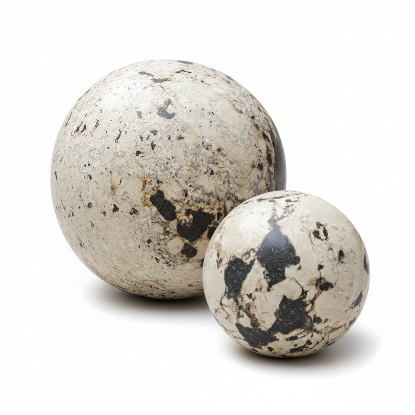 Two speckled stone balls on a white surface