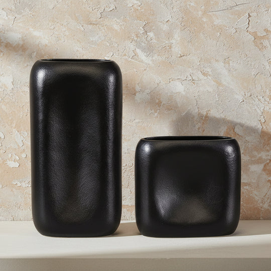 Two black ceramic vases on a neutral surface