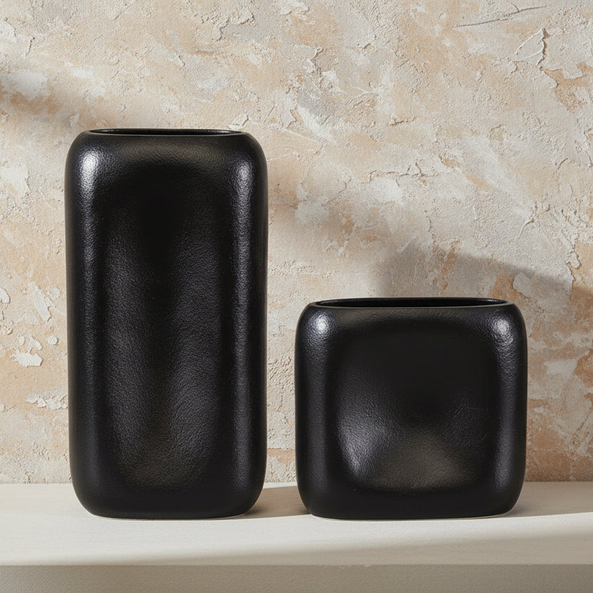 Two black ceramic vases on a neutral surface