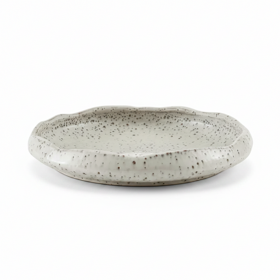 A shallow, round ceramic decorative bowl with a scalloped rim, featuring a speckled glaze in a light gray and off-white color combination.