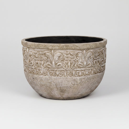Decorative stone planter with intricate patterns on a white background