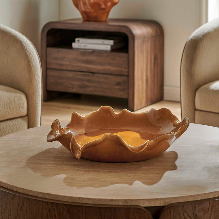 A wavy, scalloped ceramic bowl in a warm amber-brown glaze