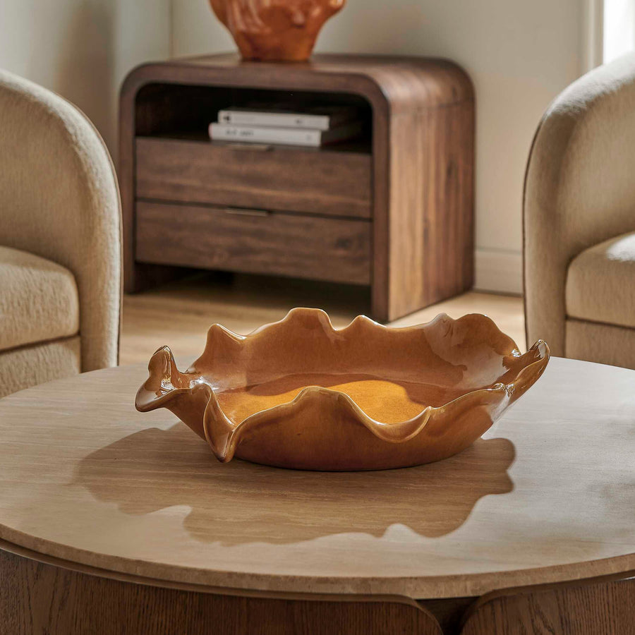A wavy, scalloped ceramic bowl in a warm amber-brown glaze
