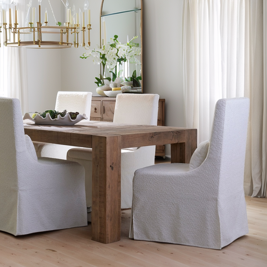Dining room with wooden table and white chairs in a bright room.