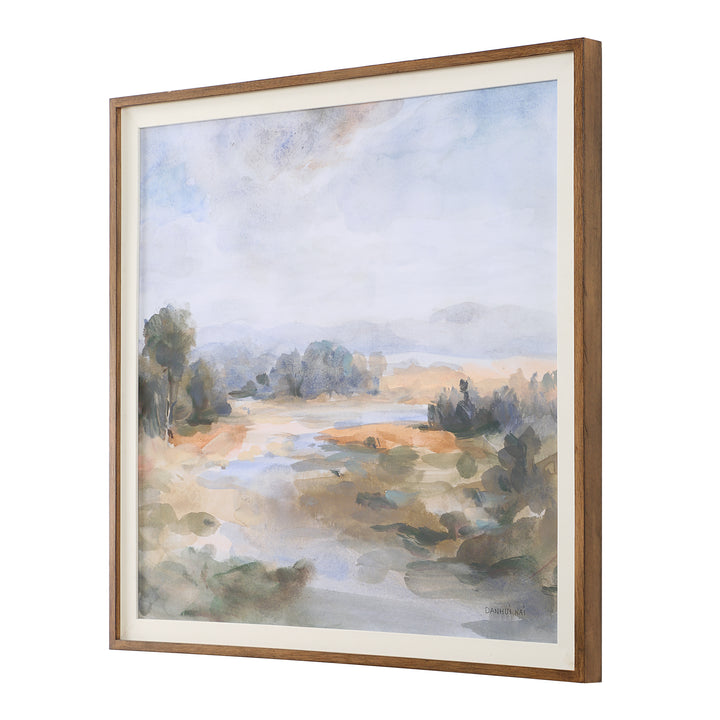 A framed print of a serene river landscape with pastel blue, olive, and rust colors, enclosed in a chestnut frame with a white linen liner