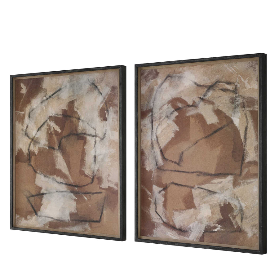 Two abstract art pieces in brown and beige tones on a wall with a wooden side table.