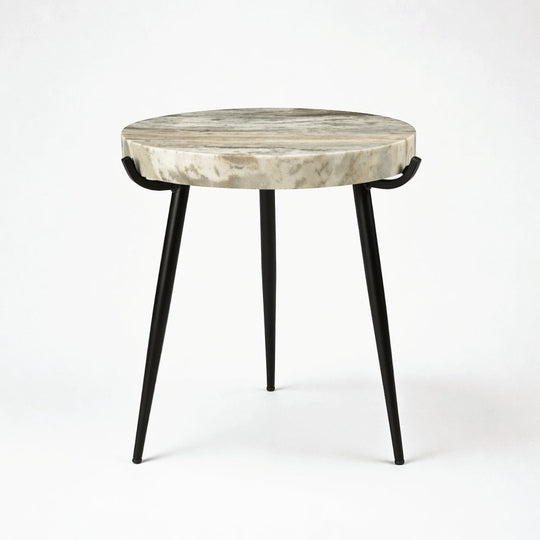 A round side table with a natural stone top featuring beige and gray marbling, supported by three slim black metal legs.