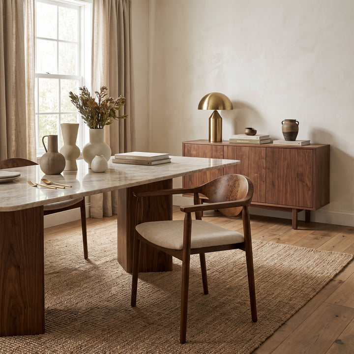 Modern dining room with a marble table, wooden chairs, and minimalist decor in a warm, neutral color palette.
