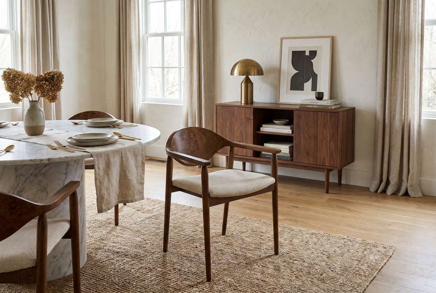 Modern dining room with a marble table, walnut chairs, and a sideboard in a warm, minimalist, and neutral-toned space.