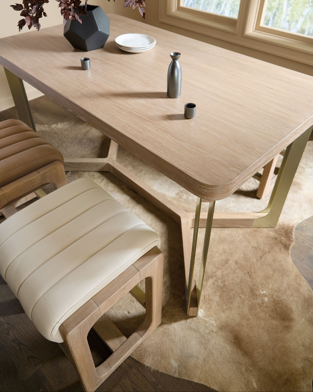 A modern wooden counter stool with slatted chairs, minimalist decor, and a soft rug beneath, illuminated by natural light.