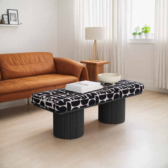 Modern living room with a brown sofa, patterned coffee table, and decorative items.