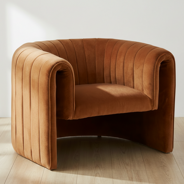Brown velvet armchair on a wooden floor with a white wall background