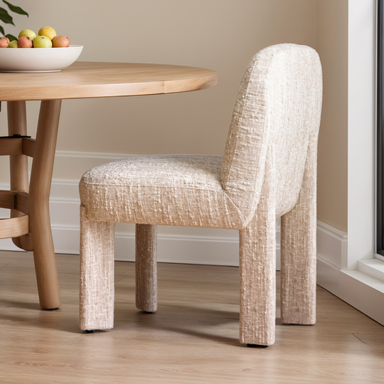 Dining chair with a textured design next to a wooden table with fruit bowl