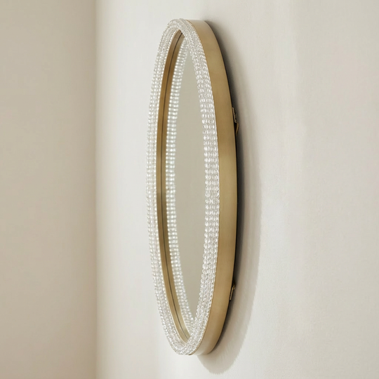 Round mirror with decorative frame on a beige wall