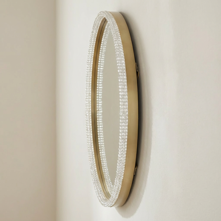 Round mirror with decorative frame on a beige wall