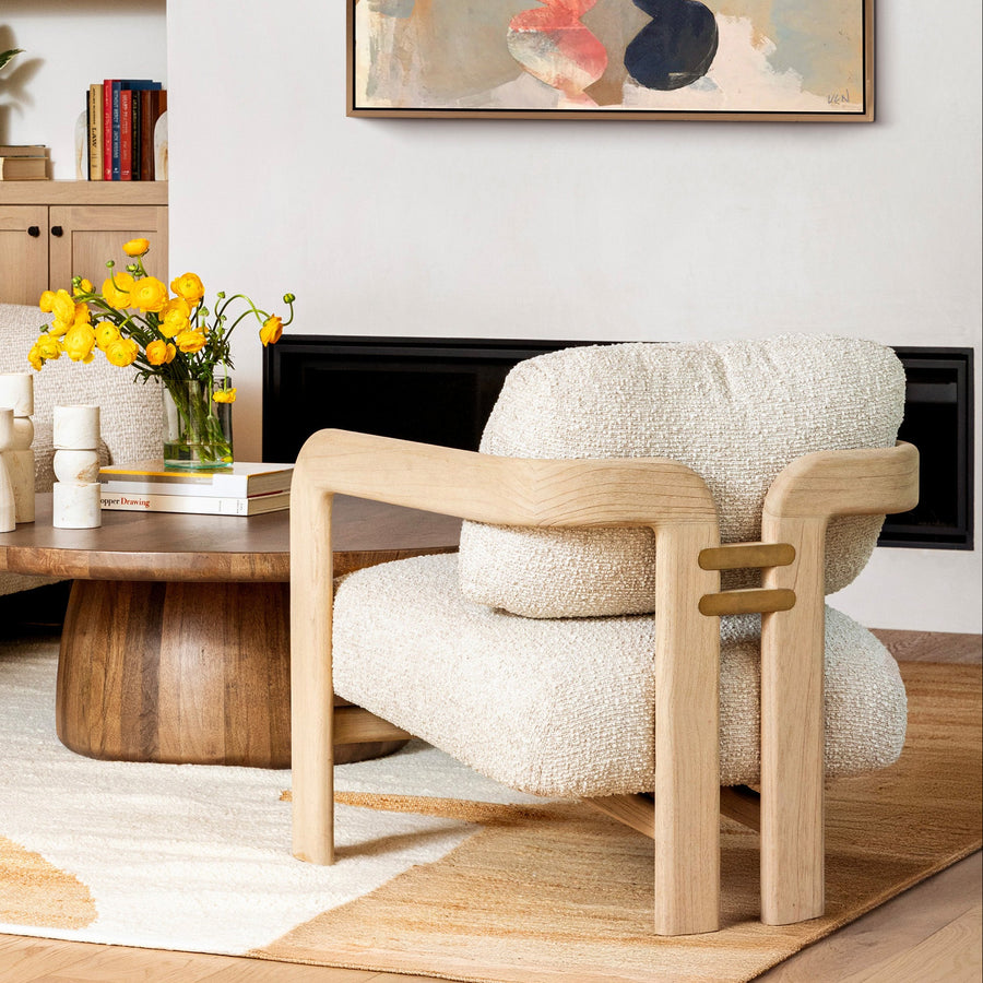 A modern accent chair featuring a light oak wood frame and plush, textured cream bouclé upholstery