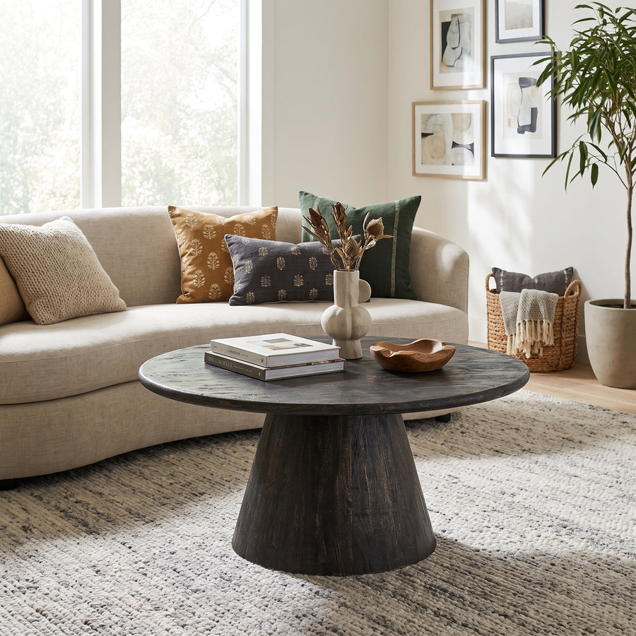 A round dark wood coffee table with a tapered pedestal base