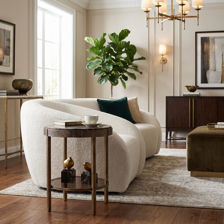 Elegant living room featuring a cream curved sofa, round side table, and modern brass chandelier in a sophisticated space.