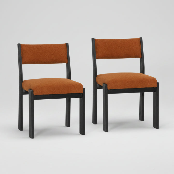 Two rust chairs with black frames on a white background