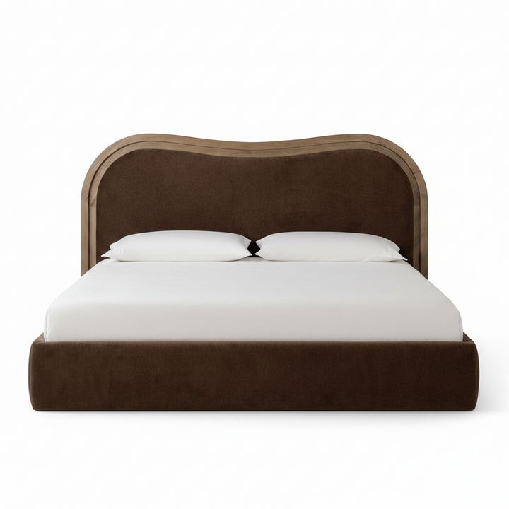 A modern platform bed with a wavy upholstered headboard in dark brown fabric and a light wood trim, shown with white bedding and two pillows on a solid white background.