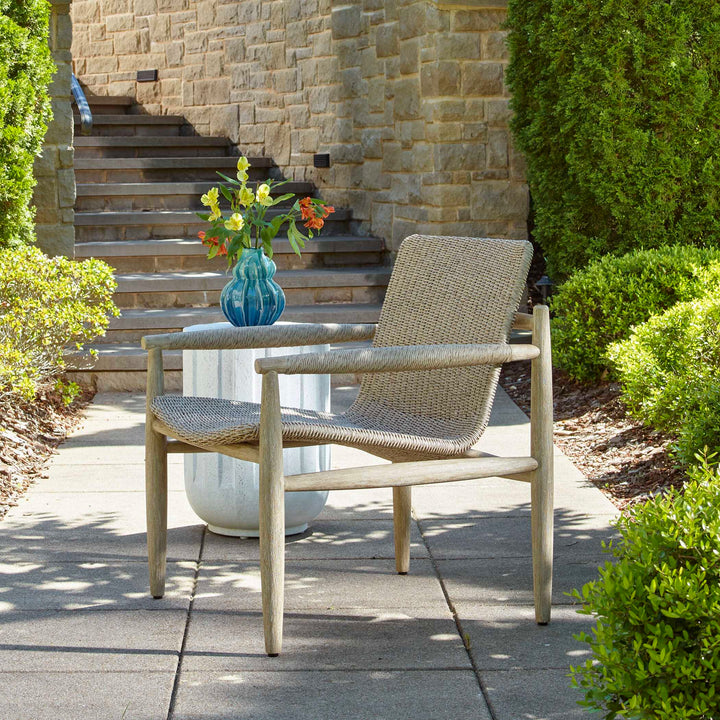 Woven chair and small table with a vase of flowers on a patio