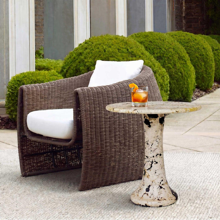 A round stone side table with a pedestal base, featuring a textured off-white surface with black, brown, and gold marbling