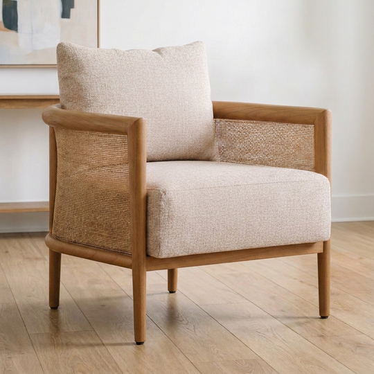 A mid-century modern accent chair with a light beige textured fabric seat and back cushion, a woven cane backrest, and a natural wood frame, set on a light wood floor.
