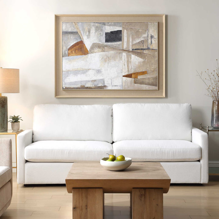 White sofa in a living room with a wooden coffee table and abstract art on the wall.