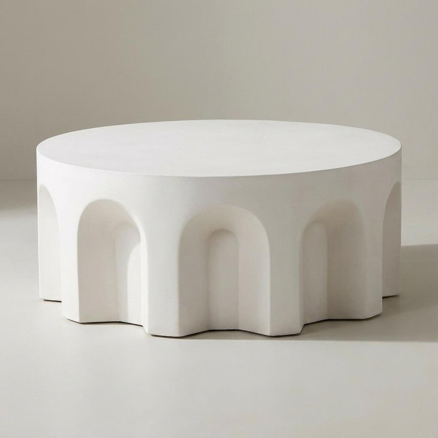 White, modernist coffee table with arch-shaped base on a neutral background