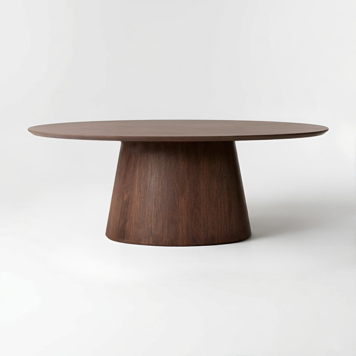 A modern oval dining table with a dark brown wood grain top and a tapered conical pedestal base, photographed on a seamless light gray studio background.