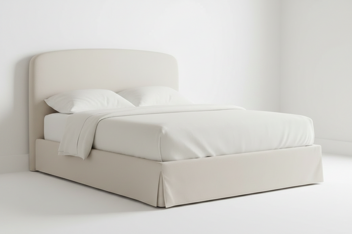 Beige upholstered bed with white bedding on a plain background