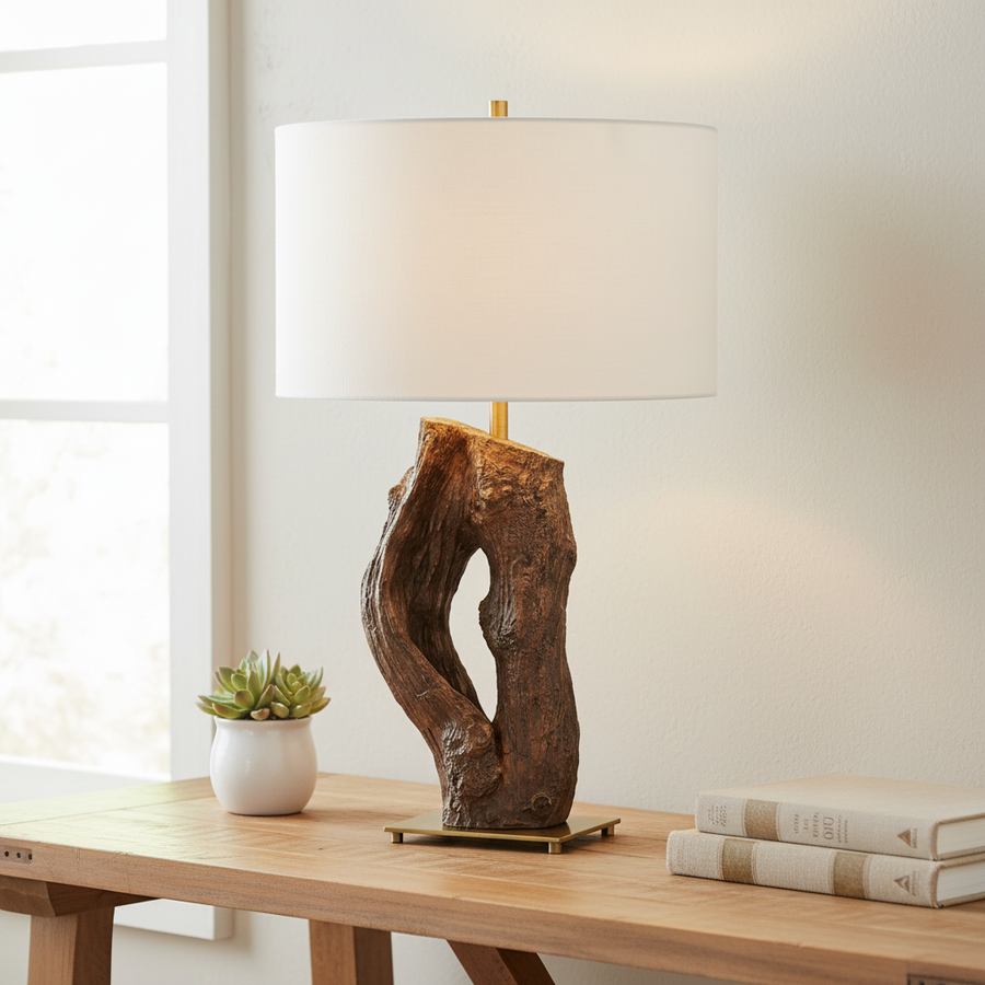 Table lamp with wooden base on a wooden table next to a plant and books.