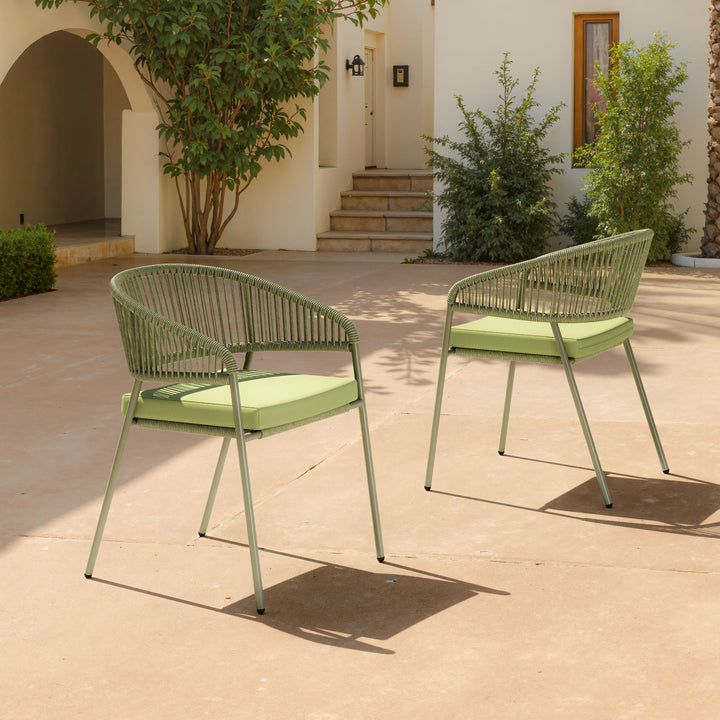 Two green outdoor chairs on a patio with a building and plants in the background