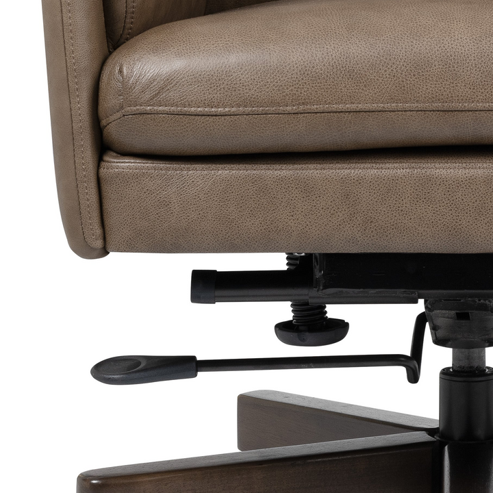 Close-up of a brown upholstered office chair showing the seat cushion, side armrest, black lever mechanism, and dark wood base on a white background.